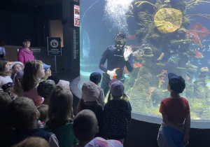 nurek macha do dzieci z wnętrza wielkiego akwarium
